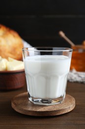 Photo of Glass with fresh milk, honey and bread on wooden table