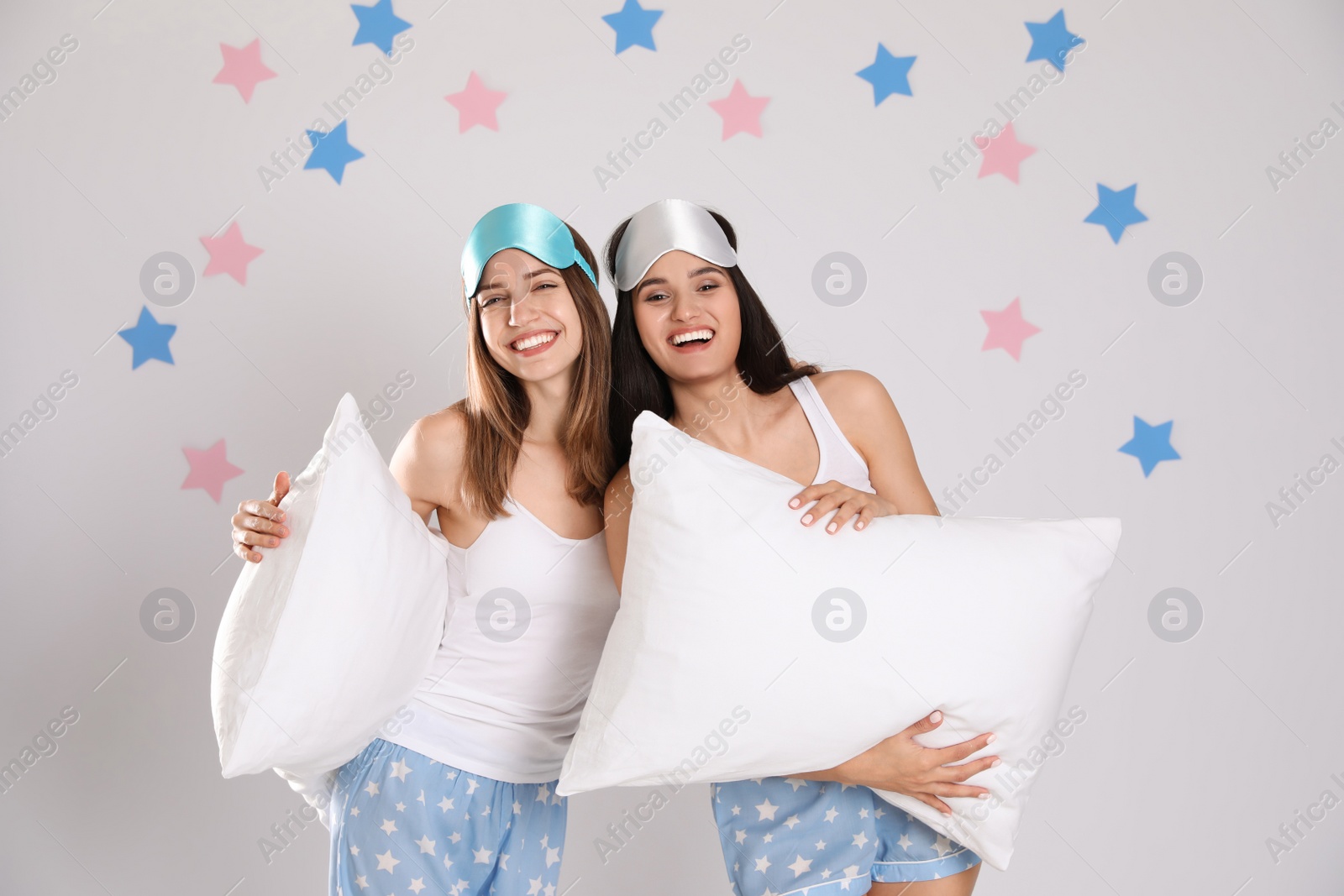 Photo of Beautiful women with pillows on light grey  background. Bedtime