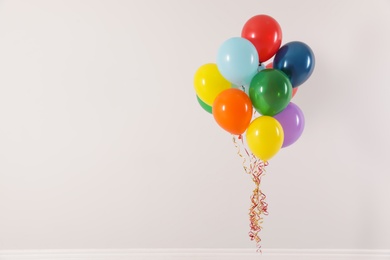 Photo of Bunch of bright balloons on light background, space for text. Celebration time