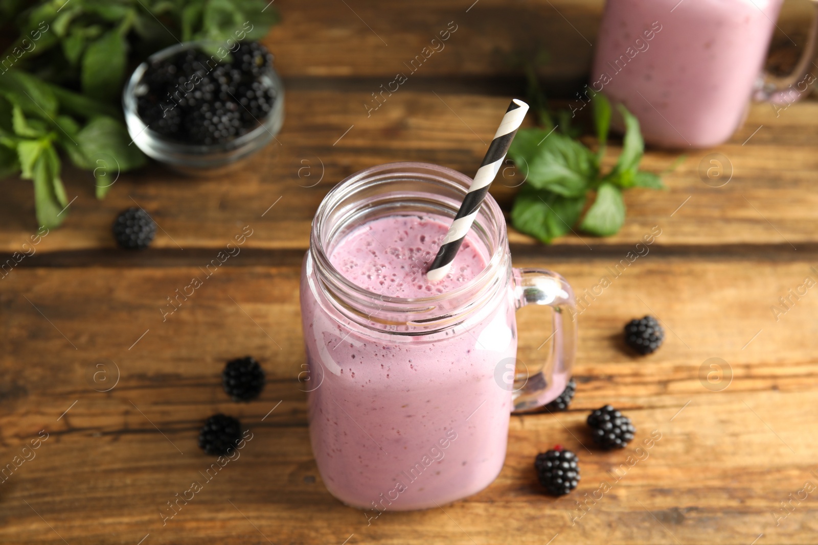 Photo of Tasty fresh milk shake with blackberries on wooden table