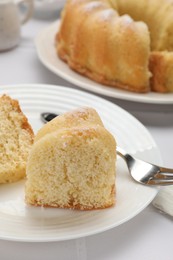 Photo of Pieces of delicious sponge cake and fork on white table, closeup