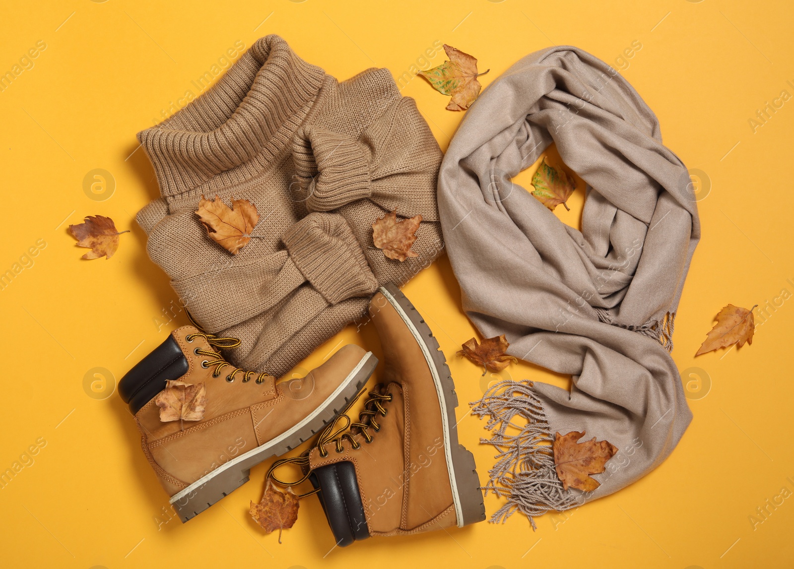 Photo of Flat lay composition with sweater and dry leaves on yellow background. Autumn season