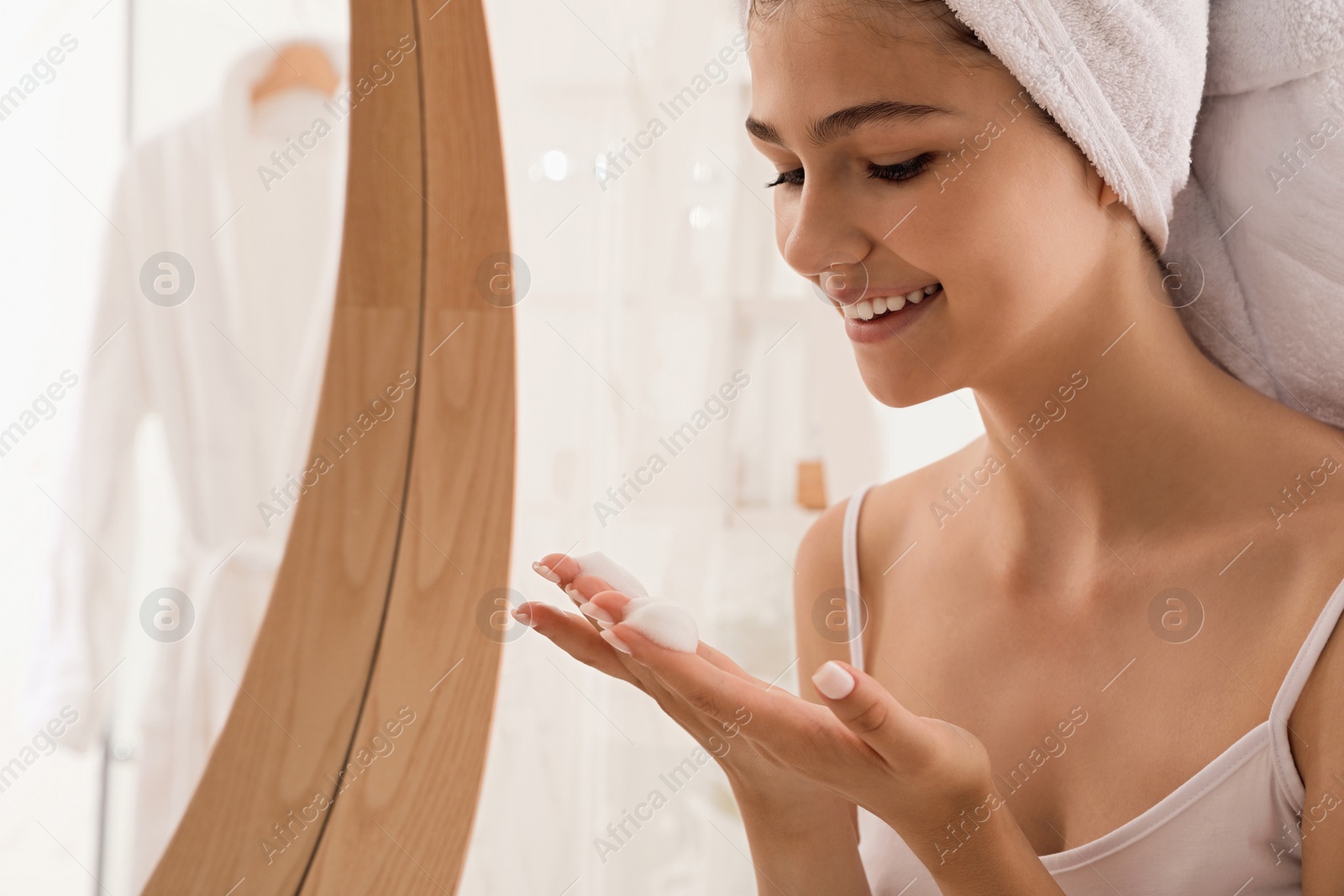 Photo of Beautiful teenage girl applying cleansing foam onto face at home, space for text. Skin care cosmetic