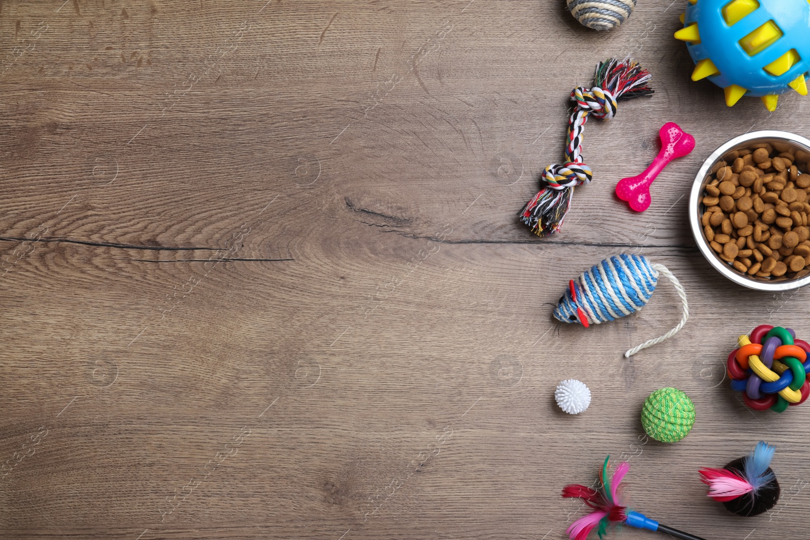 Photo of Flat lay composition with different pet toys and feeding bowl on wooden background, space for text