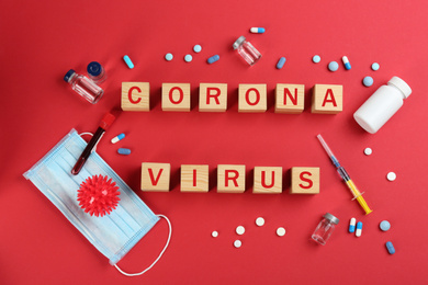 Photo of Wooden cubes with words CORONA VIRUS and medicine on red background, flat lay