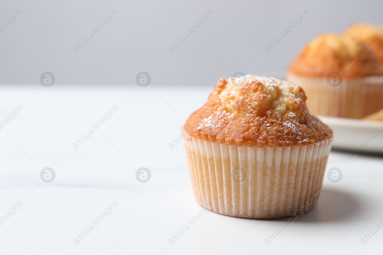 Photo of Delicious sweet muffin on white table, closeup. Space for text