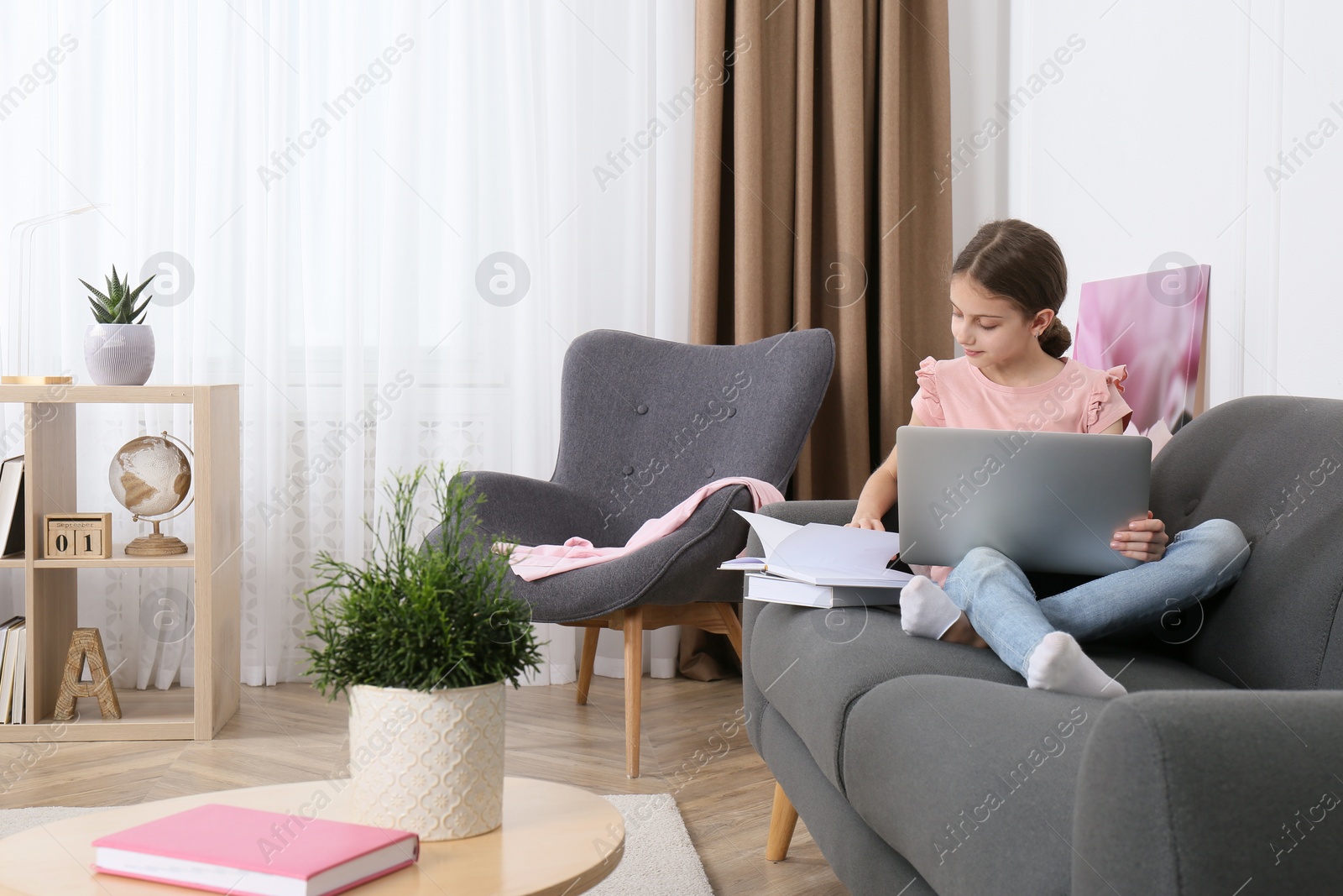 Photo of Girl with laptop and books on sofa at home