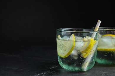 Soda water with lemon slices and ice cubes on grey table. Space for text