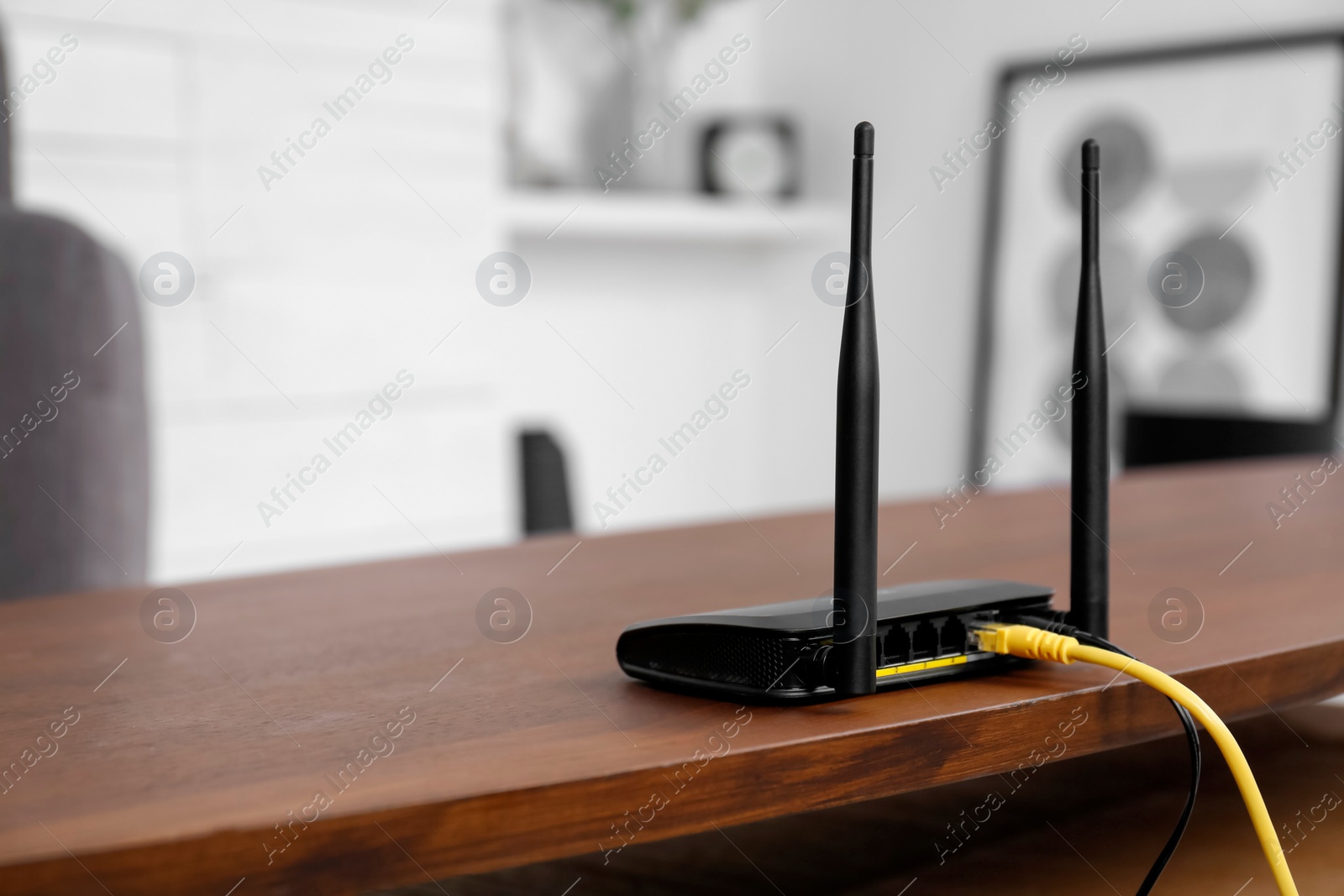 Photo of Modern Wi-Fi router on wooden table indoors. Space for text