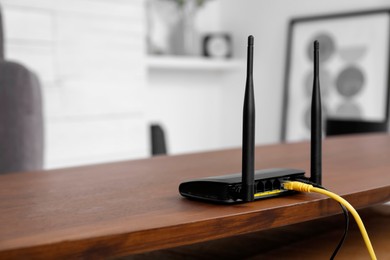 Photo of Modern Wi-Fi router on wooden table indoors. Space for text