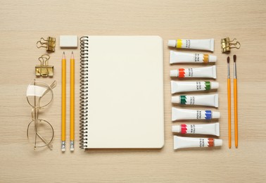 Flat lay composition with blank sketchbook on wooden table. Space for text