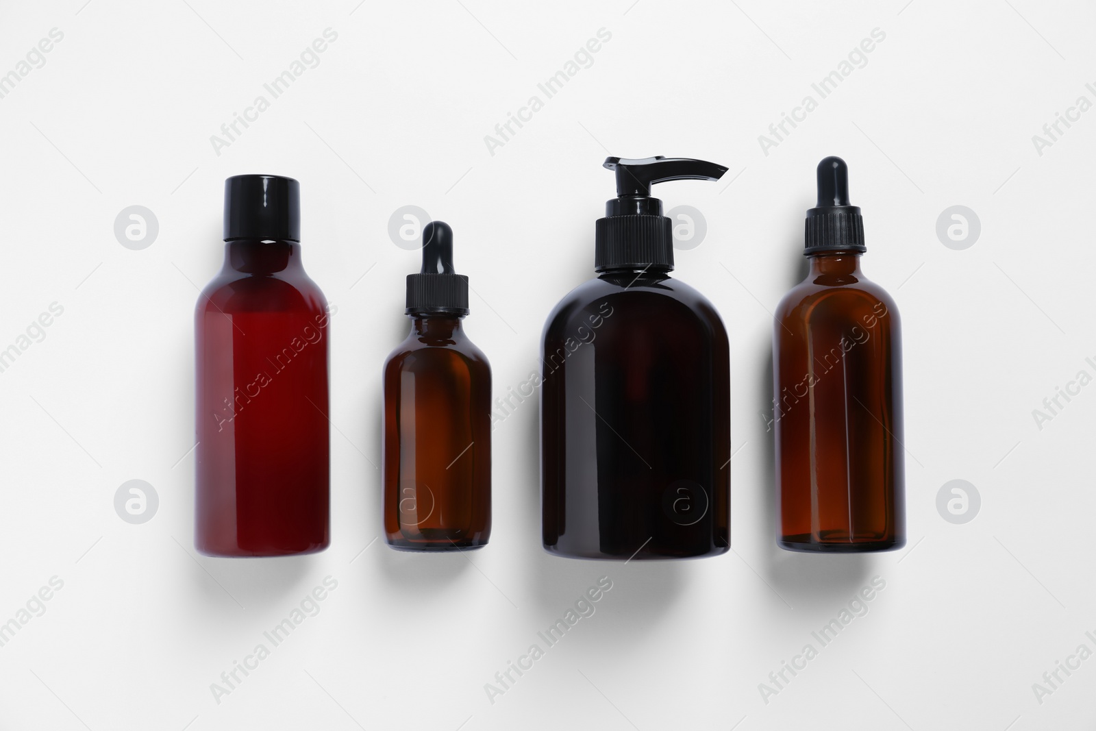 Photo of Bottles with different cosmetic products on white background, flat lay