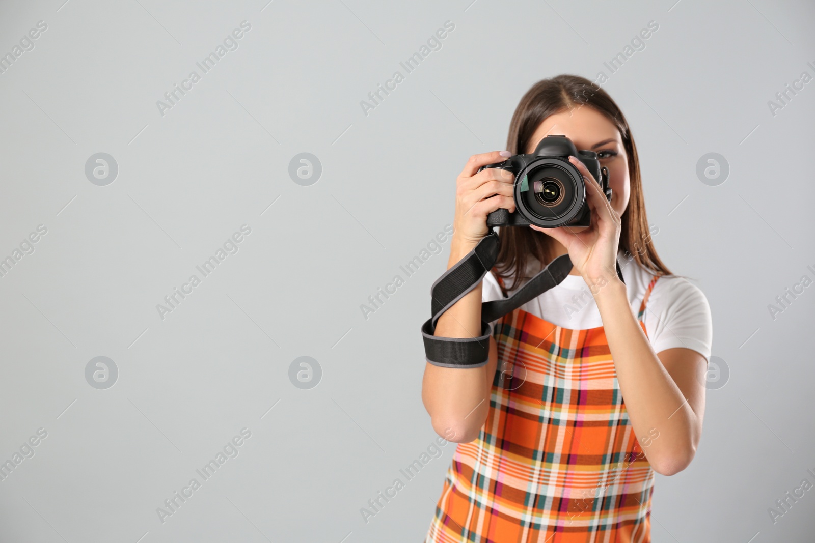 Photo of Professional photographer working on light grey background in studio. Space for text
