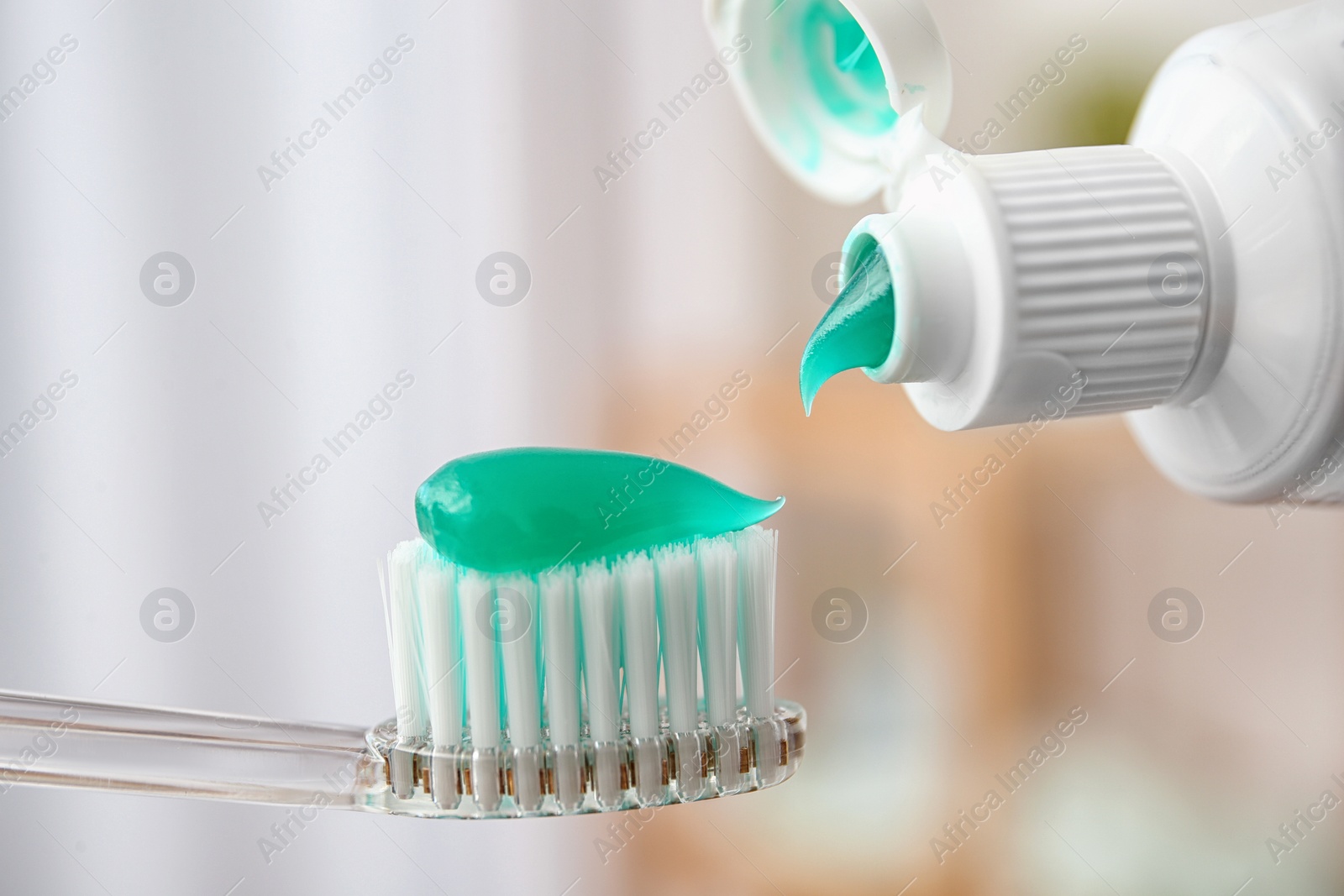 Photo of Applying paste on toothbrush against blurred background, closeup