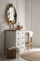 Photo of Modern room interior with chest of drawers and mirror on white wall