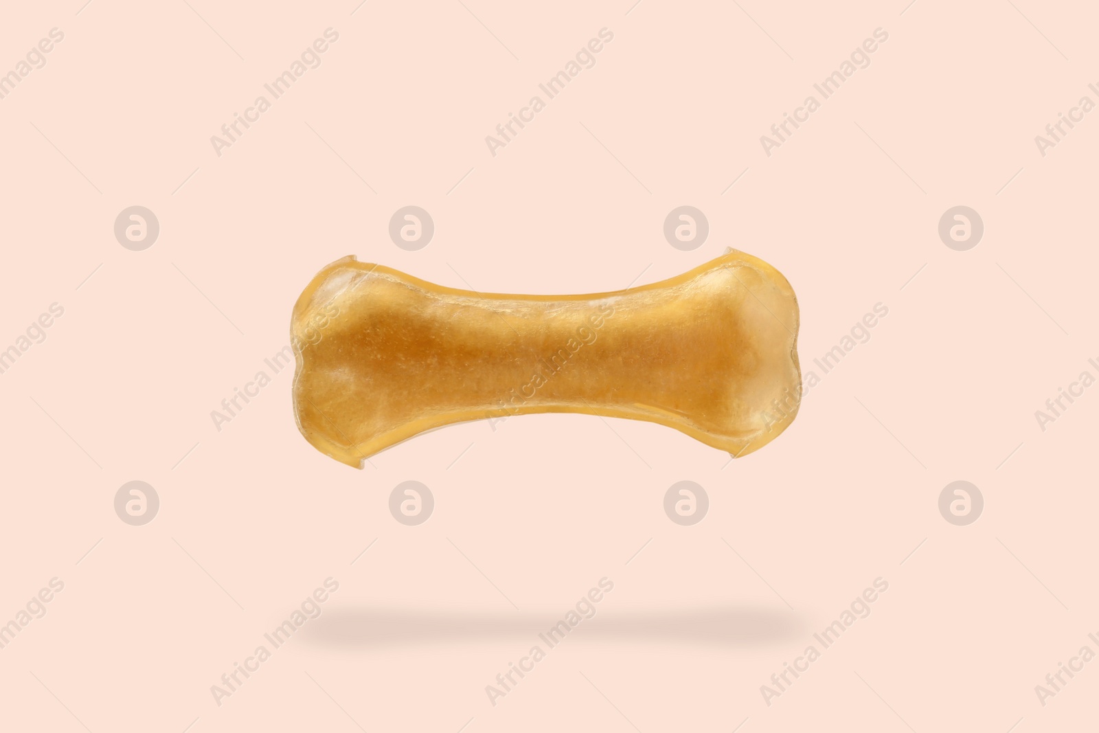 Image of Bone dog treat in air on beige pink background