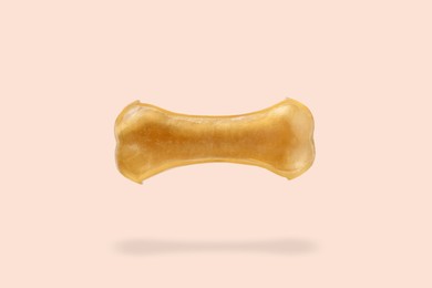 Bone dog treat in air on beige pink background