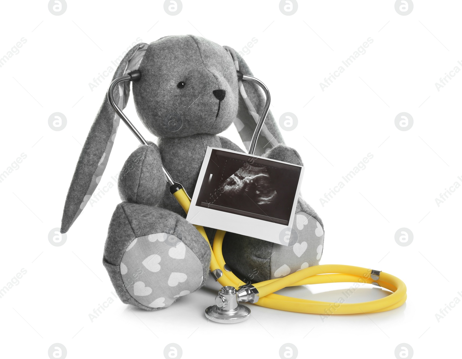 Photo of Ultrasound photo of baby and toy rabbit on white background. Concept of pregnancy