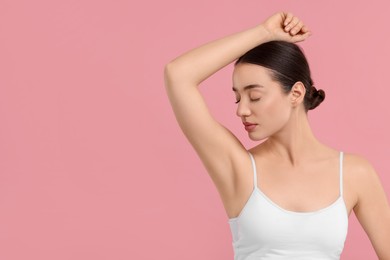 Beautiful woman showing armpit with smooth clean skin on pink background, space for text