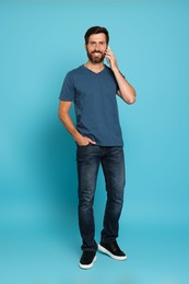 Photo of Happy man talking on phone against light blue background