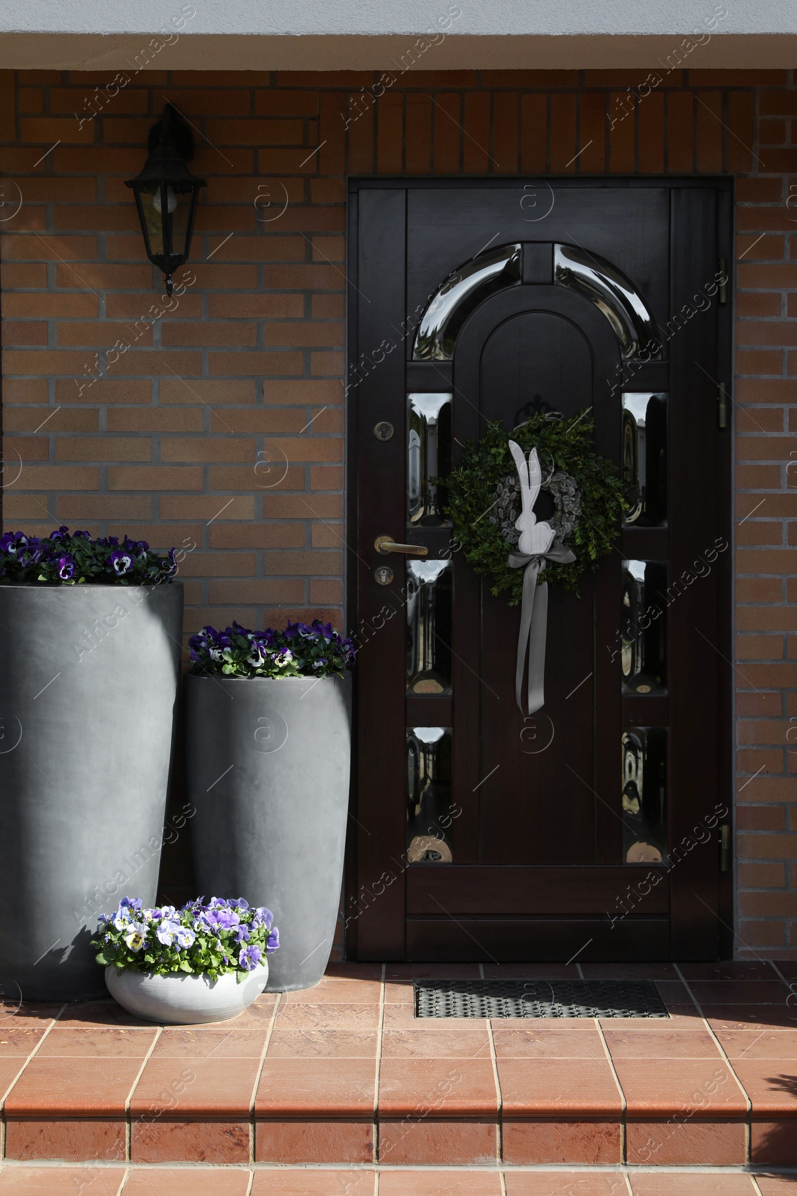 Photo of Beautiful wreath with bunny and bow hanging on door outdoors. Easter celebration