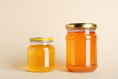 Jars with different types of organic honey on beige background