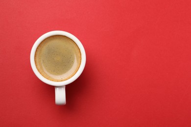 Photo of Aromatic coffee in cup on red background, top view. Space for text