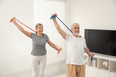 Photo of Senior couple doing exercise with fitness elastic bands at home