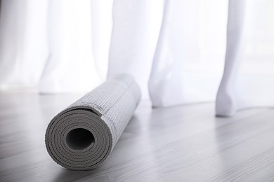 Photo of Rolled karemat or fitness mat on wooden floor. Space for text