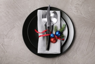 Photo of Plates, cutlery, napkin and Christmas decor on grey background, top view