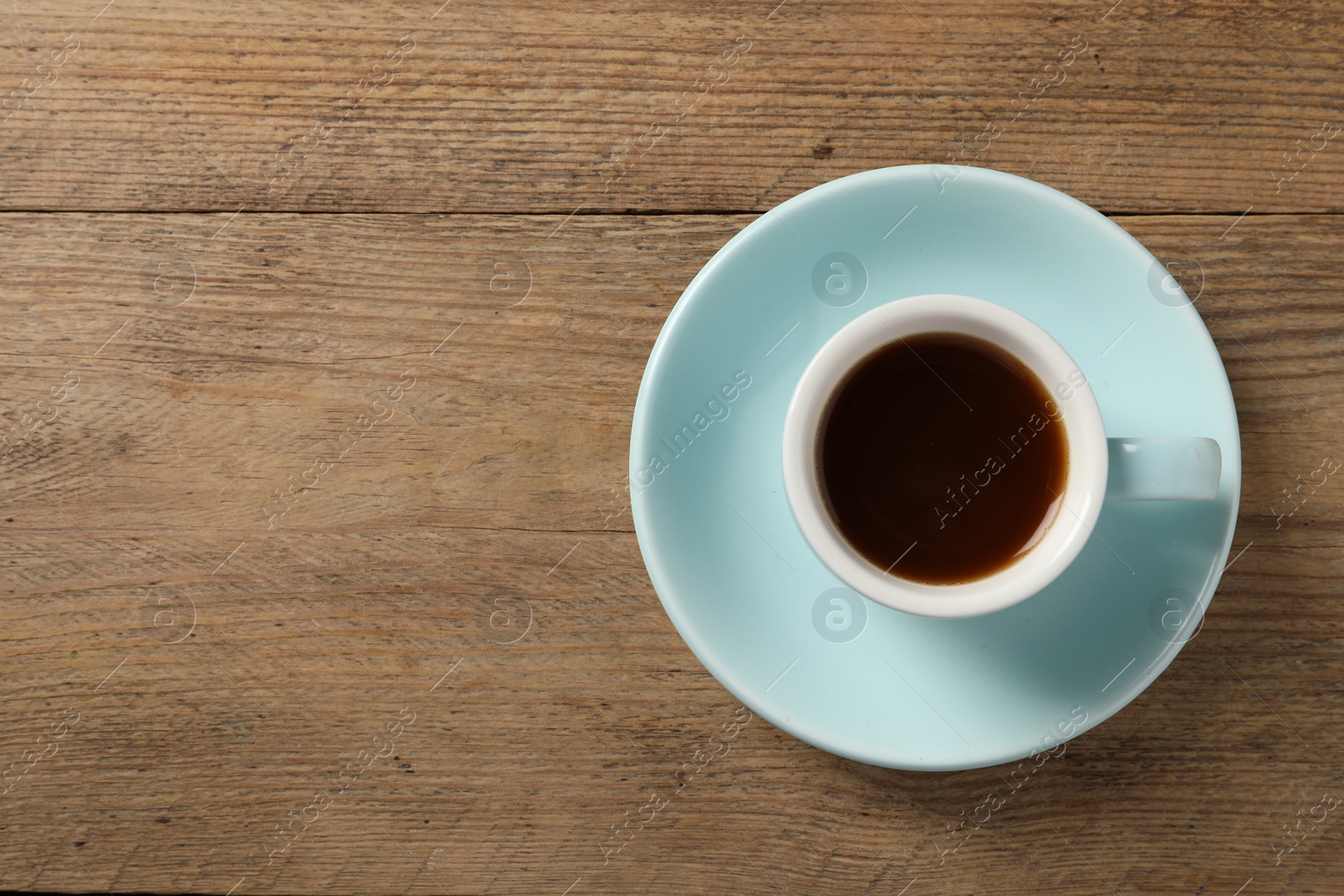 Photo of Tasty coffee in cup on wooden table, top view. Space for text