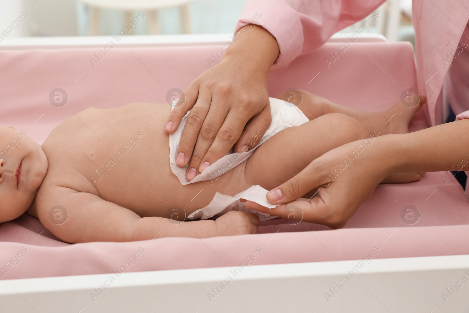 Photo of Mother changing her baby's diaper on table at home, closeup
