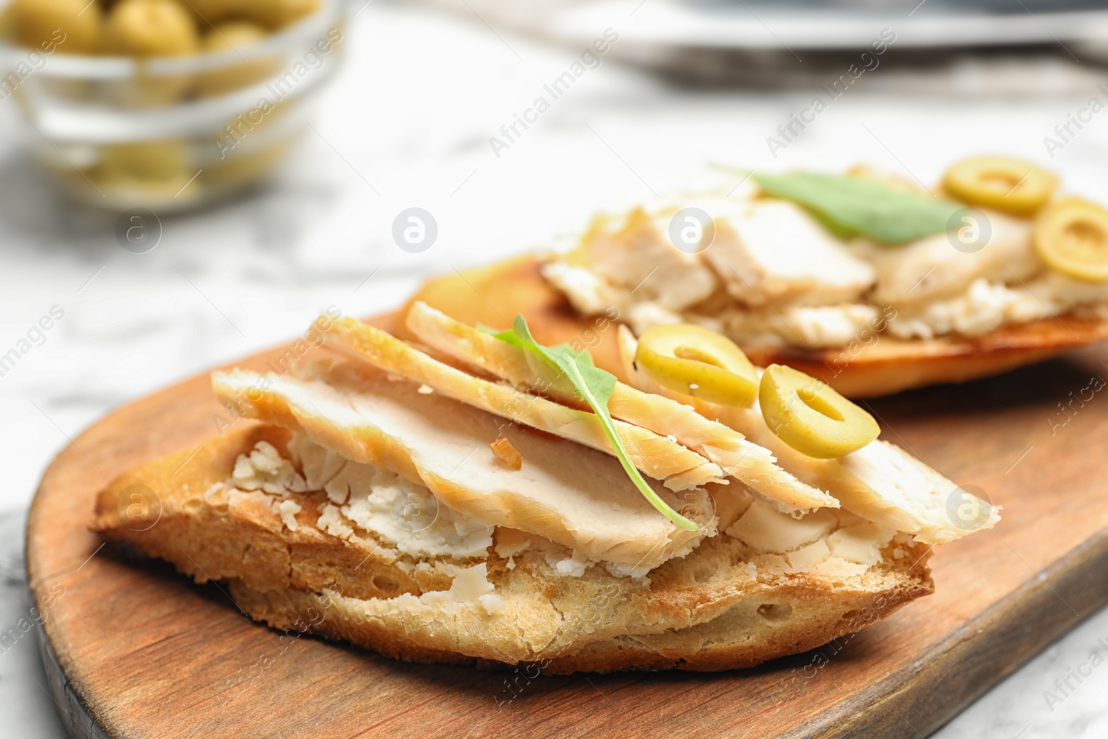 Photo of Board with delicious chicken bruschettas on table, closeup