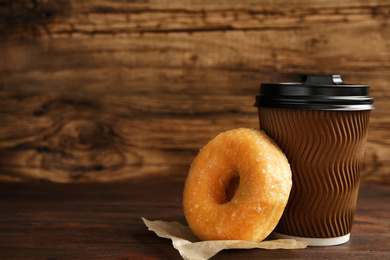Delicious donut and cup of coffee on wooden table