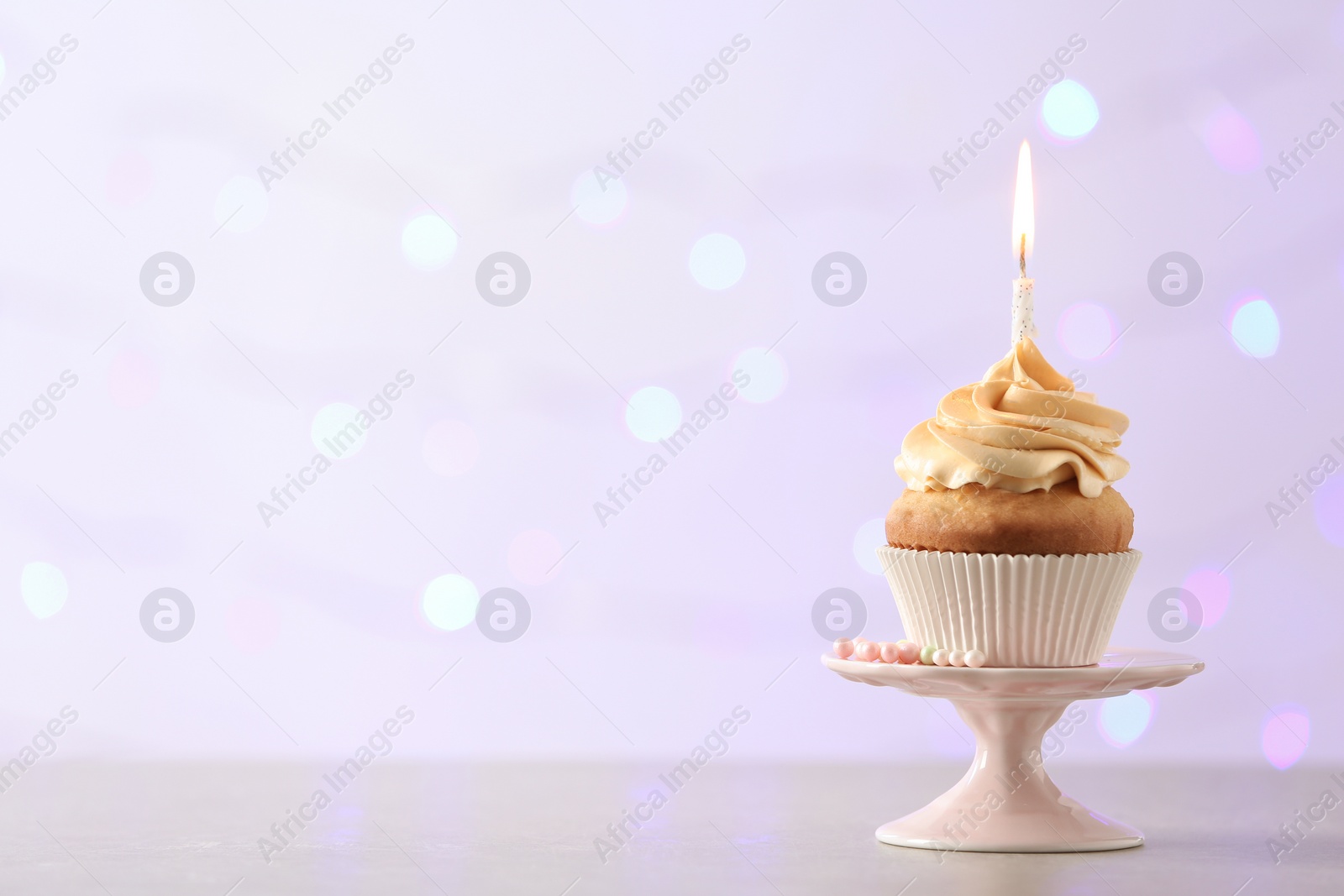 Photo of Delicious birthday cupcake with burning candle and space for text on blurred lights background