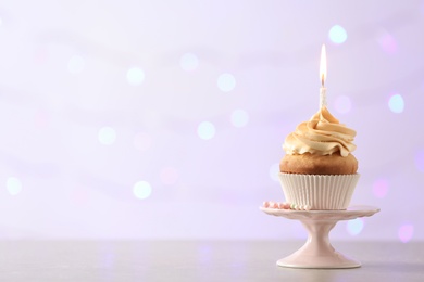 Photo of Delicious birthday cupcake with burning candle and space for text on blurred lights background