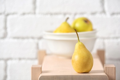 Photo of Ripe pear on wooden shelf against blurred background. Space for text