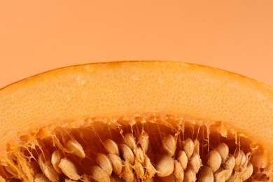 Photo of Cut fresh ripe pumpkin with seeds on pale orange background, closeup