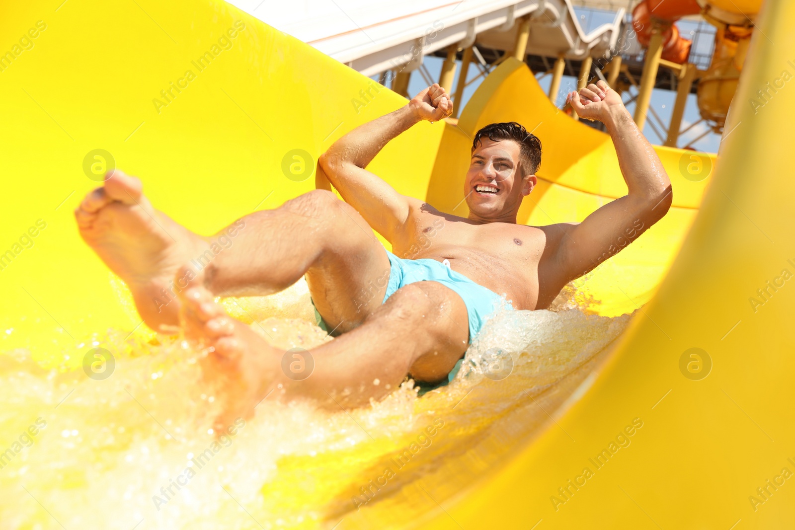 Photo of Man on slide at water park. Summer vacation