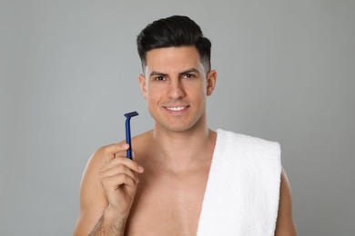 Photo of Handsome man with razor after shaving on grey background