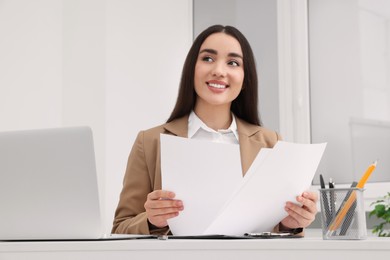 Young female intern working with laptop at table in office