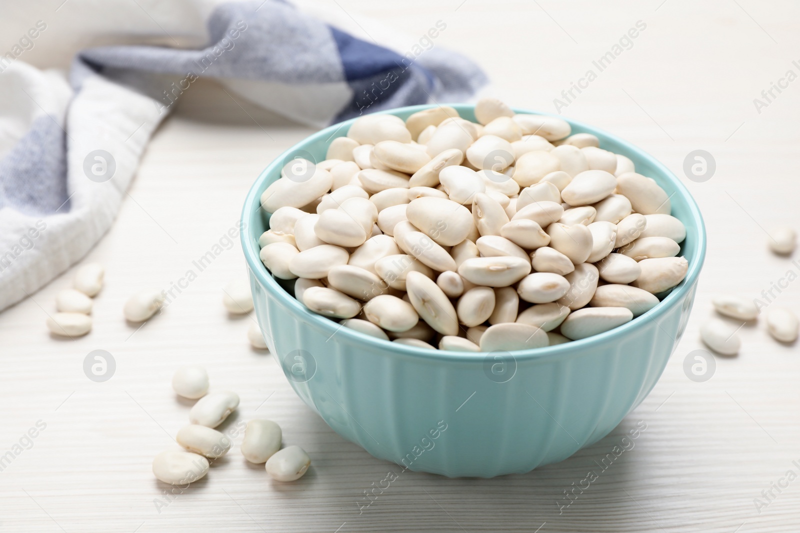 Photo of Raw beans on white wooden table, closeup