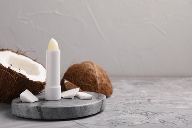 Lip balm and coconut on grey textured table, space for text