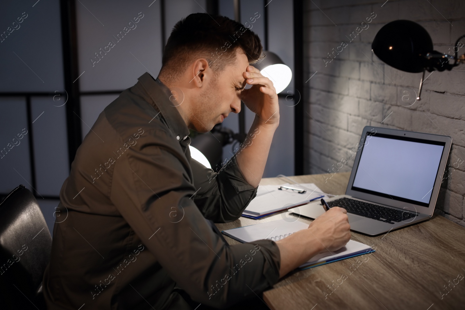 Photo of Overworked man with headache in office