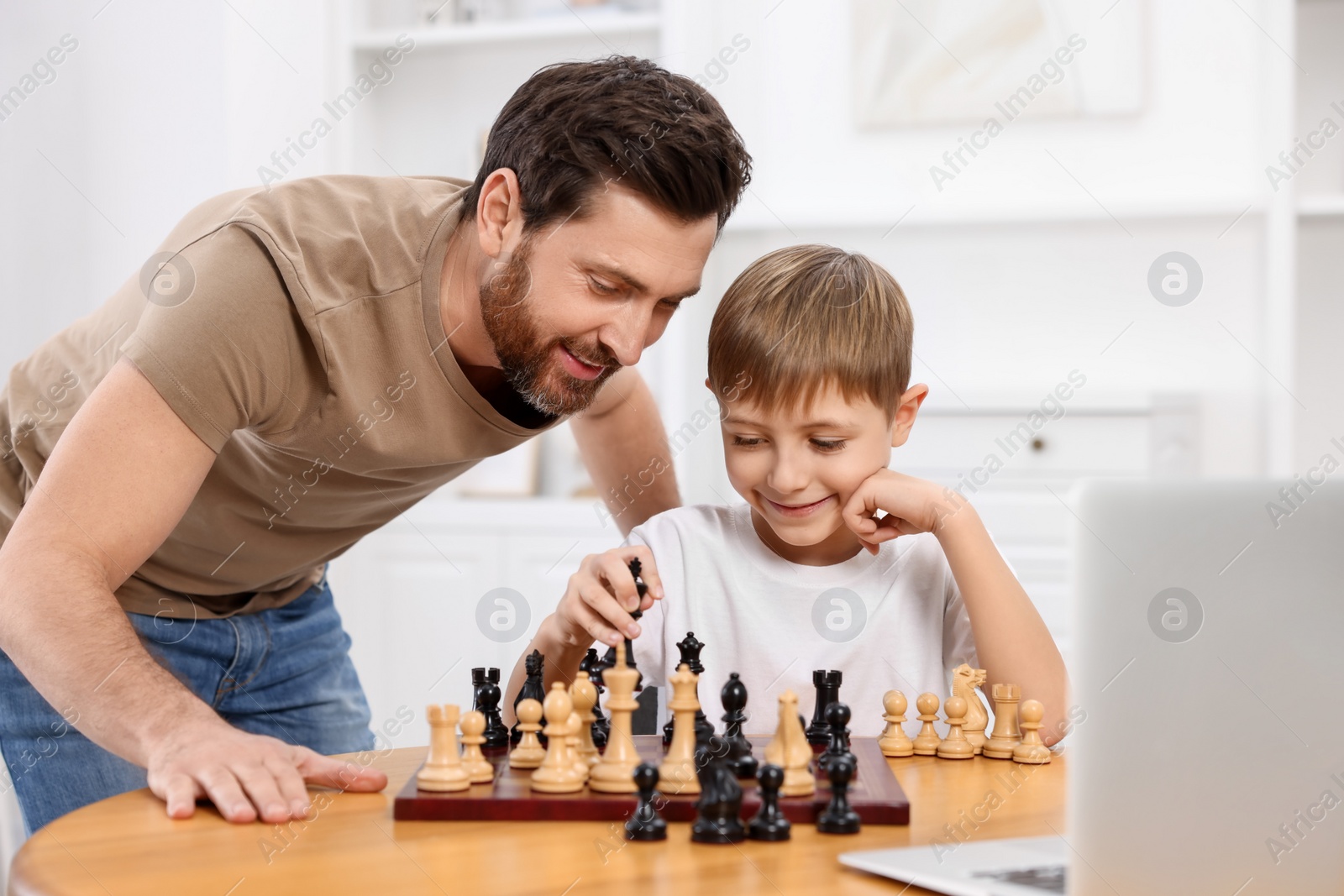 Photo of Father teaching his son to play chess following online lesson at home