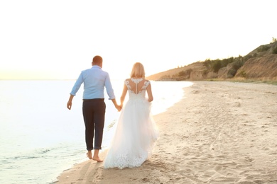 Wedding couple holding hands together on beach. Space for text