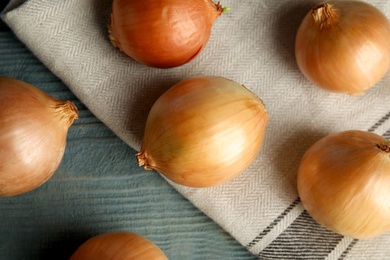 Photo of Flat lay composition with ripe onions and fabric on blue wooden table