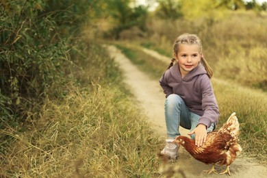 Photo of Farm animal. Cute little girl with chicken in countryside, space for text