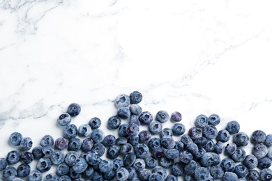 Tasty frozen blueberries on white marble table, flat lay. Space for text