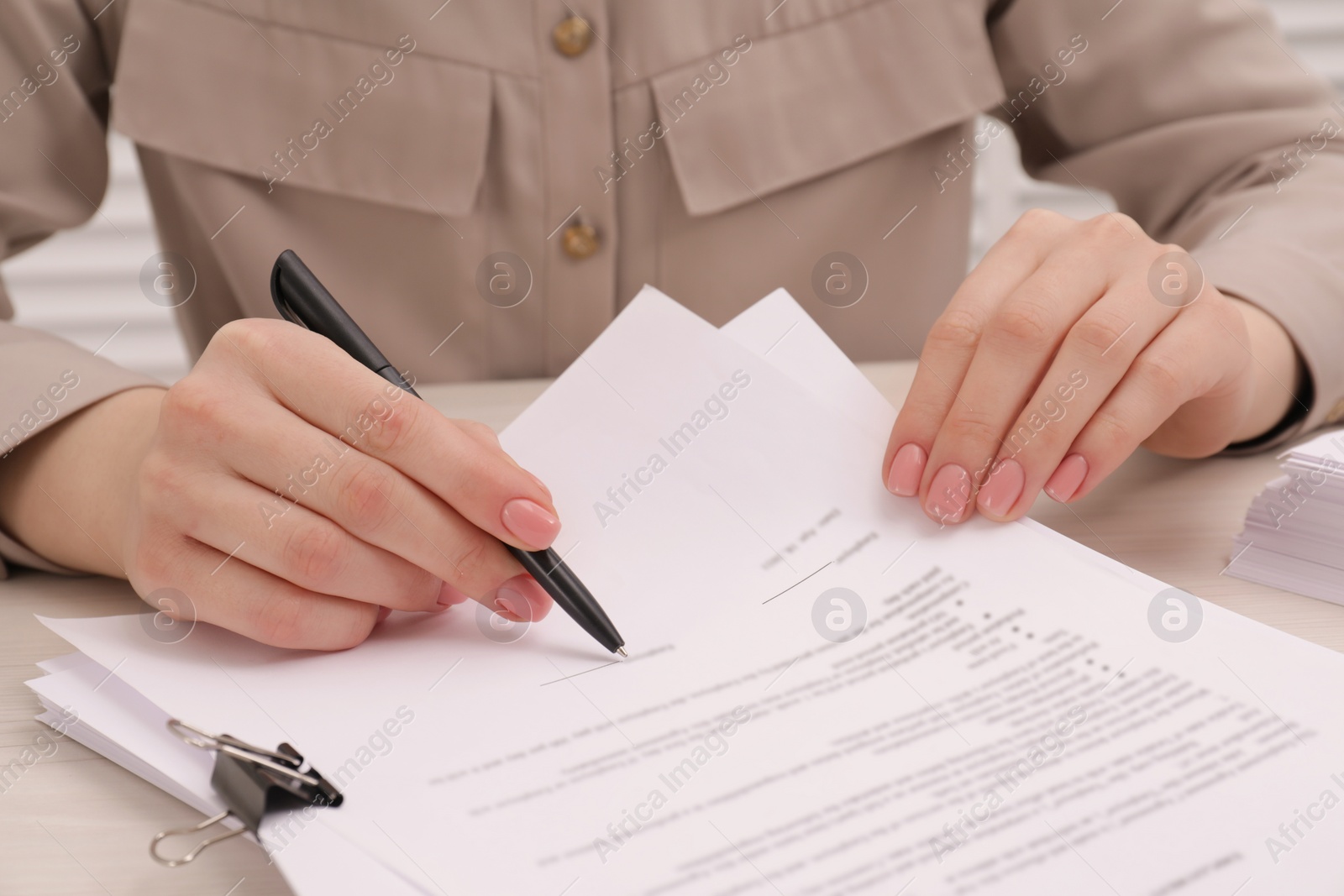 Photo of Woman signing document at wooden table, closeup